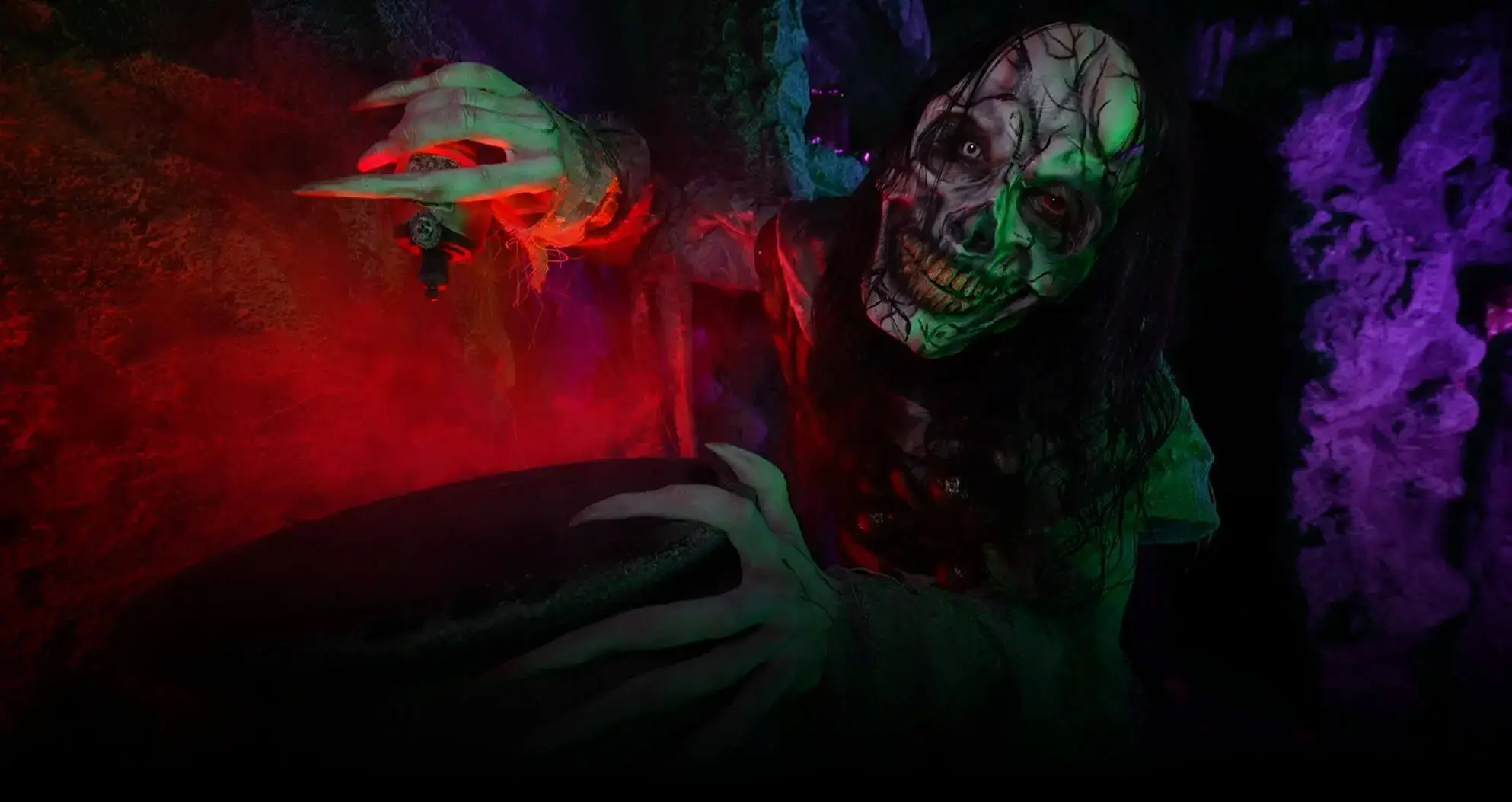 Red and green glowing witch animatronic stirring a cauldron at Bay Area haunted house